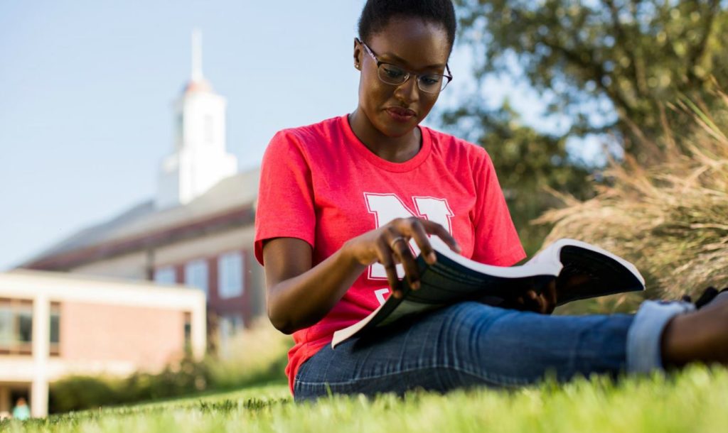 student reading while seating on grass
